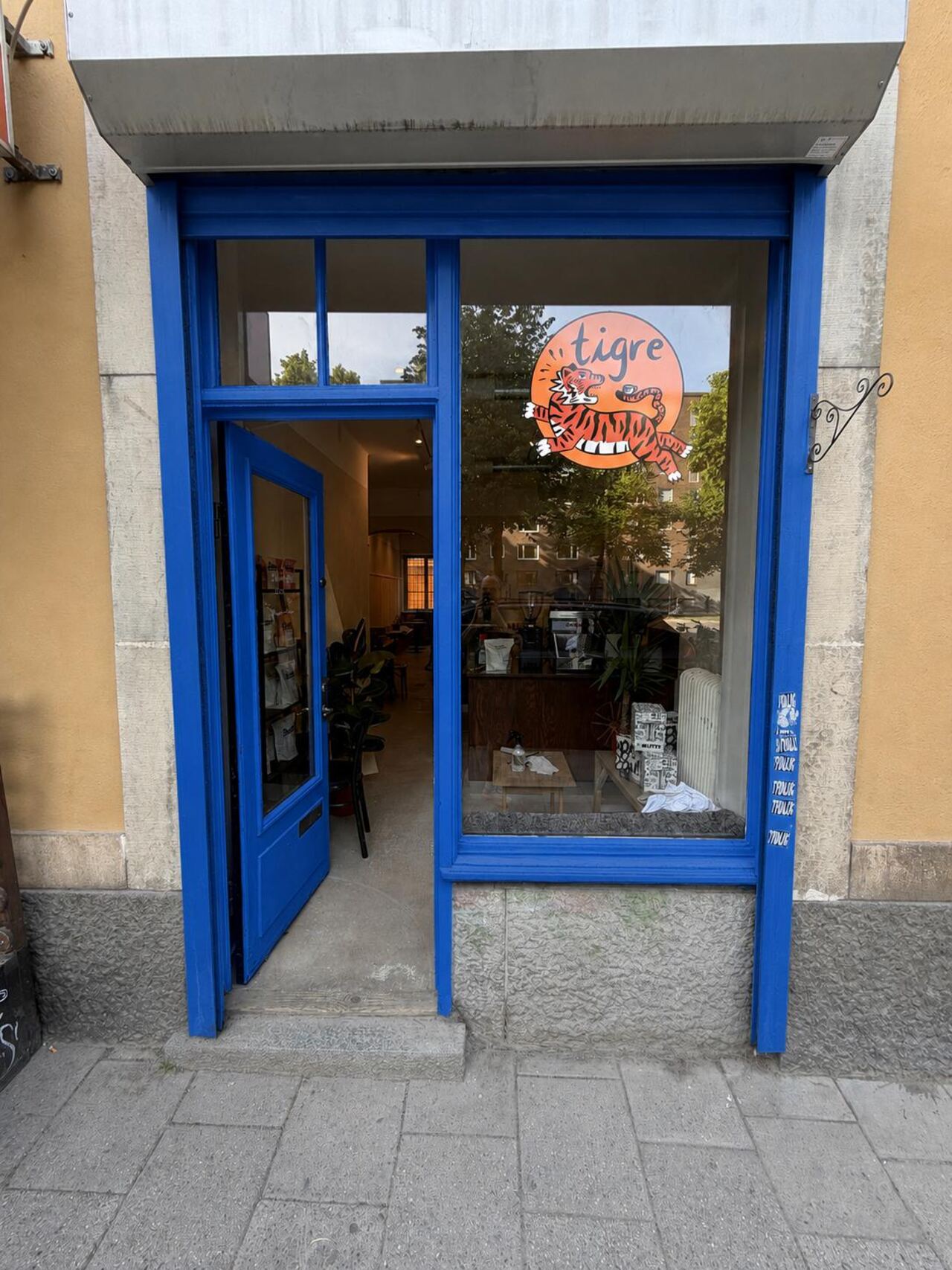 The blue-framed storefront of Tigre Kaffebar with the tiger logo on the window