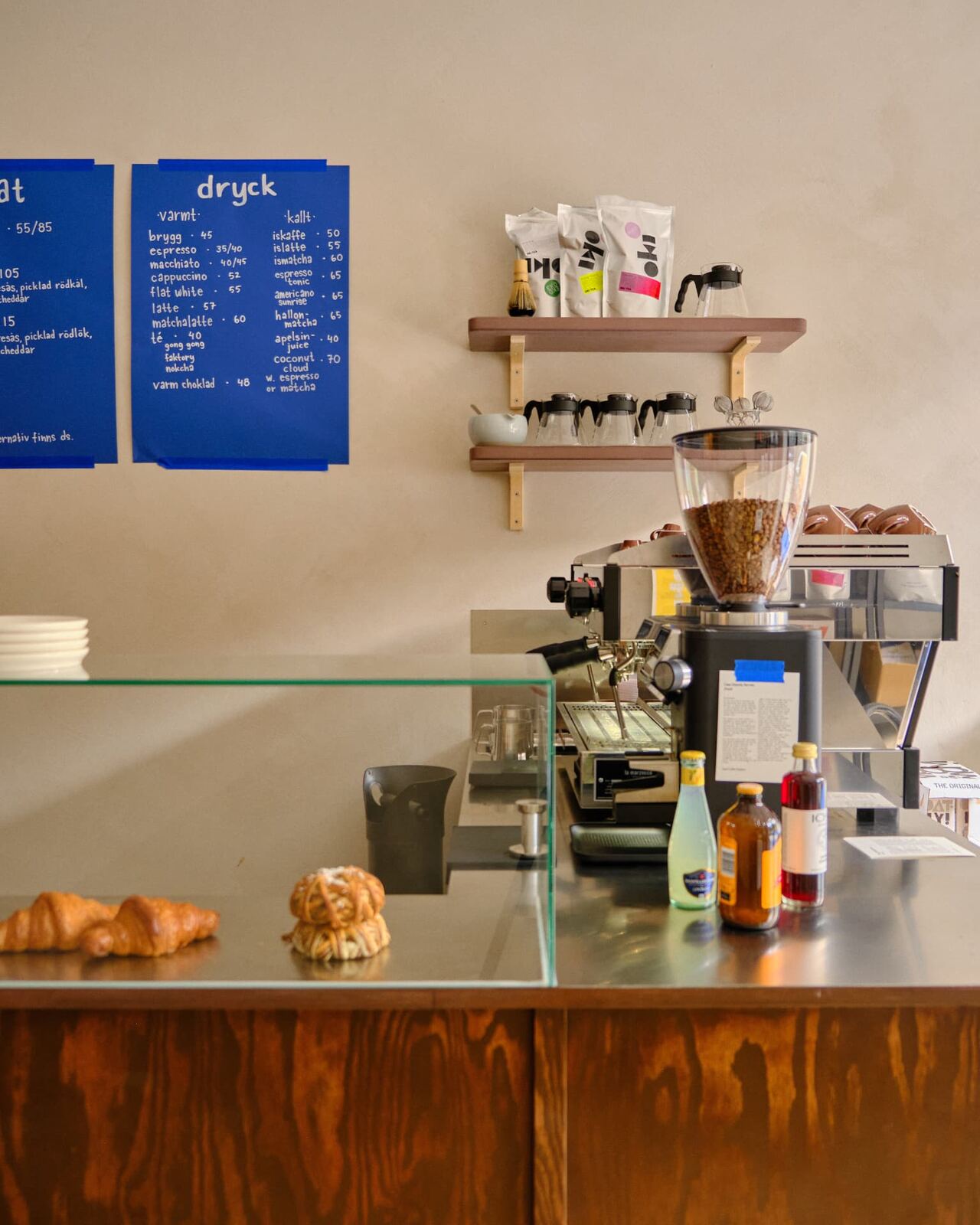 The blue menu board and shelves of coffee bags at the counter of Tigre Kaffebar
